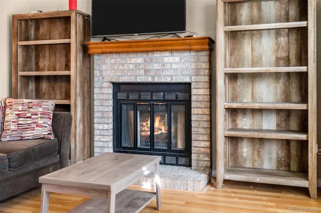 a view of an empty room with wooden floor and a fireplace