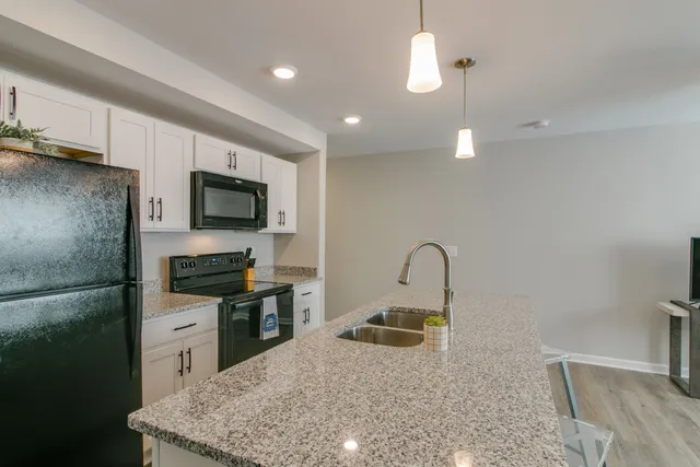 a kitchen with stainless steel appliances granite countertop a sink a stove and a refrigerator