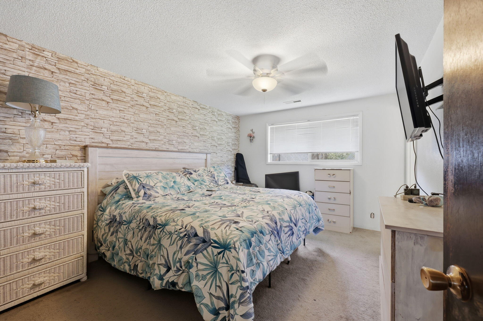 a bedroom with a bed and a flat tv screen on dresser