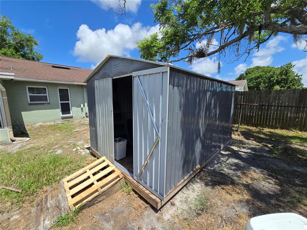 3406 Murrow Street New Port Richey, FL 34655 - Photo 19 of 21 a backyard of a house with a small barn and wooden fence