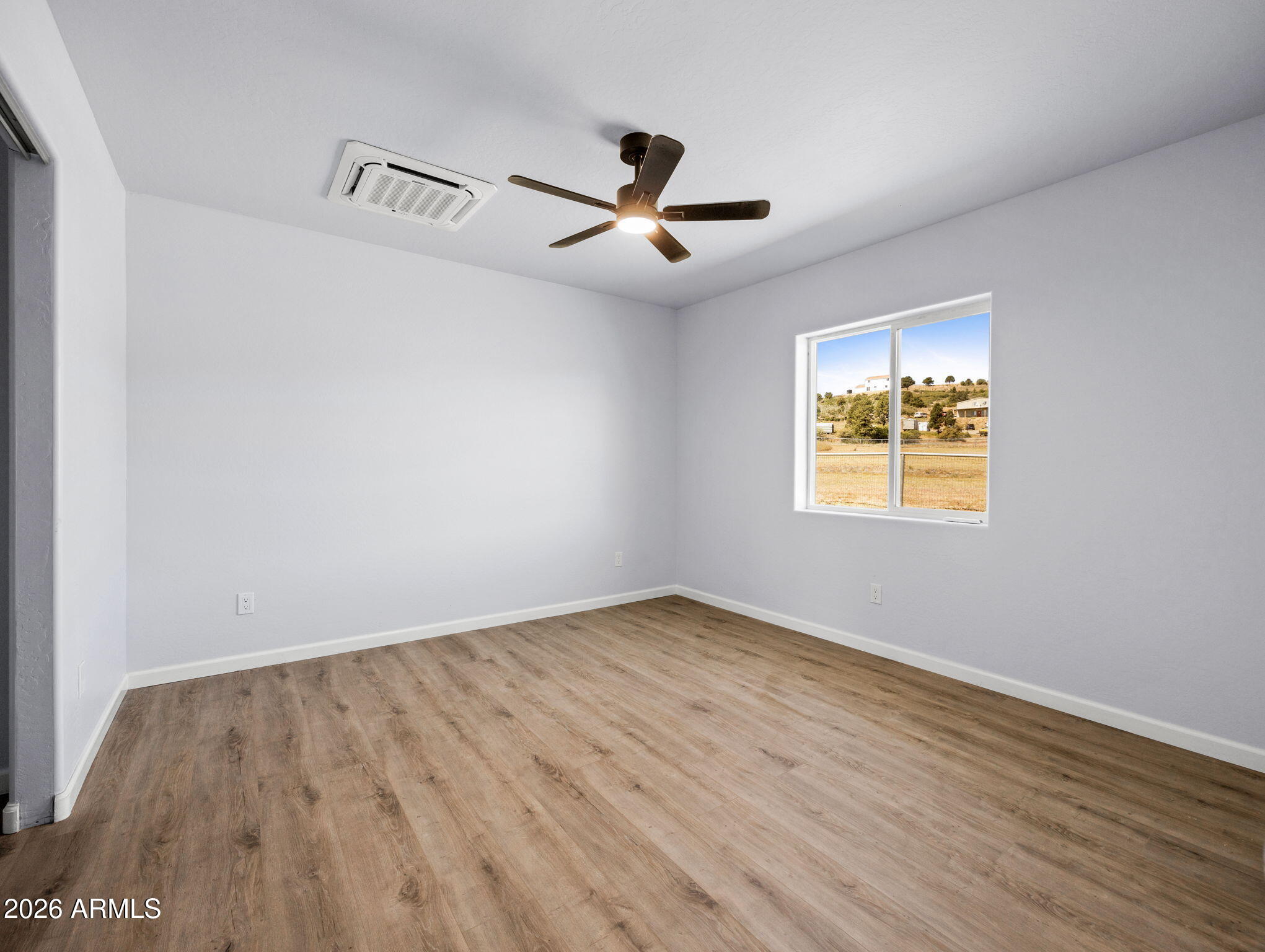 18278 Frontier Road Peeples Valley, AZ 86332 - Photo 22 of 31 an empty room with wooden floor ceiling fan and windows