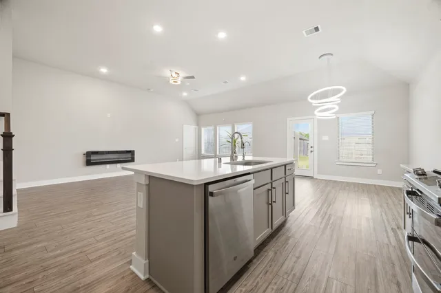 a large kitchen with stainless steel appliances a large counter top a sink and a refrigerator