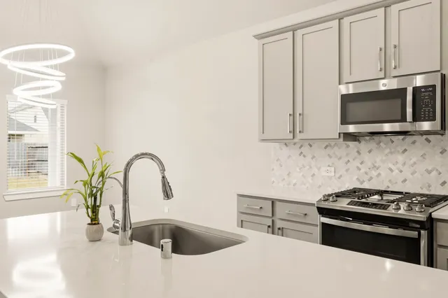 a kitchen with stainless steel appliances granite countertop a sink a stove a microwave and cabinets