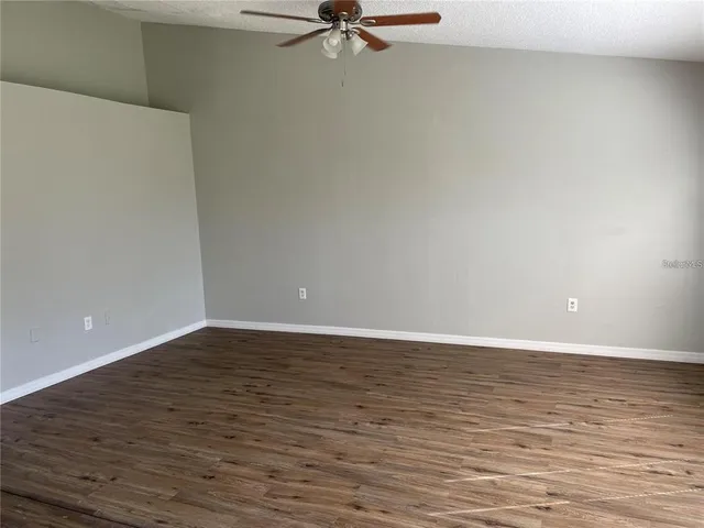 a view of a room with wooden floor and a ceiling fan