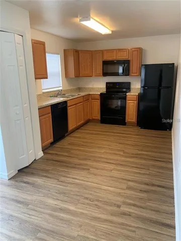 a kitchen with stainless steel appliances granite countertop a stove top oven a sink and a refrigerator