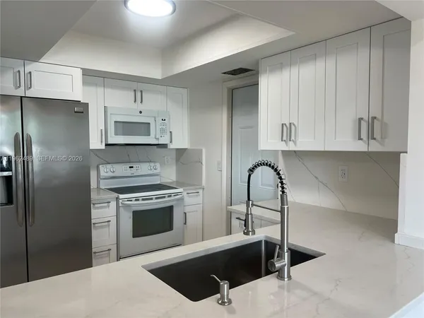 a kitchen with stainless steel appliances kitchen island a refrigerator sink and cabinets
