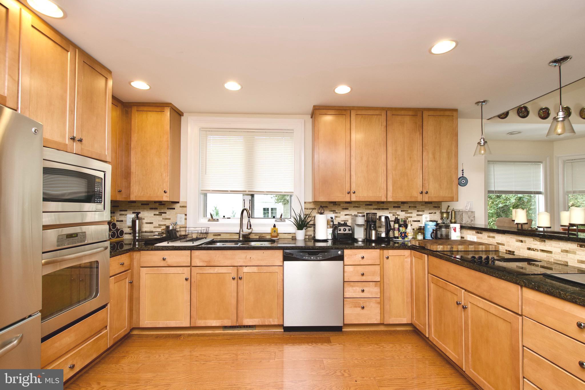 8312 Upper Spring Lane Annandale, VA 22003 - Photo 17 of 56 a kitchen with stainless steel appliances granite countertop a sink a stove top oven and refrigerator