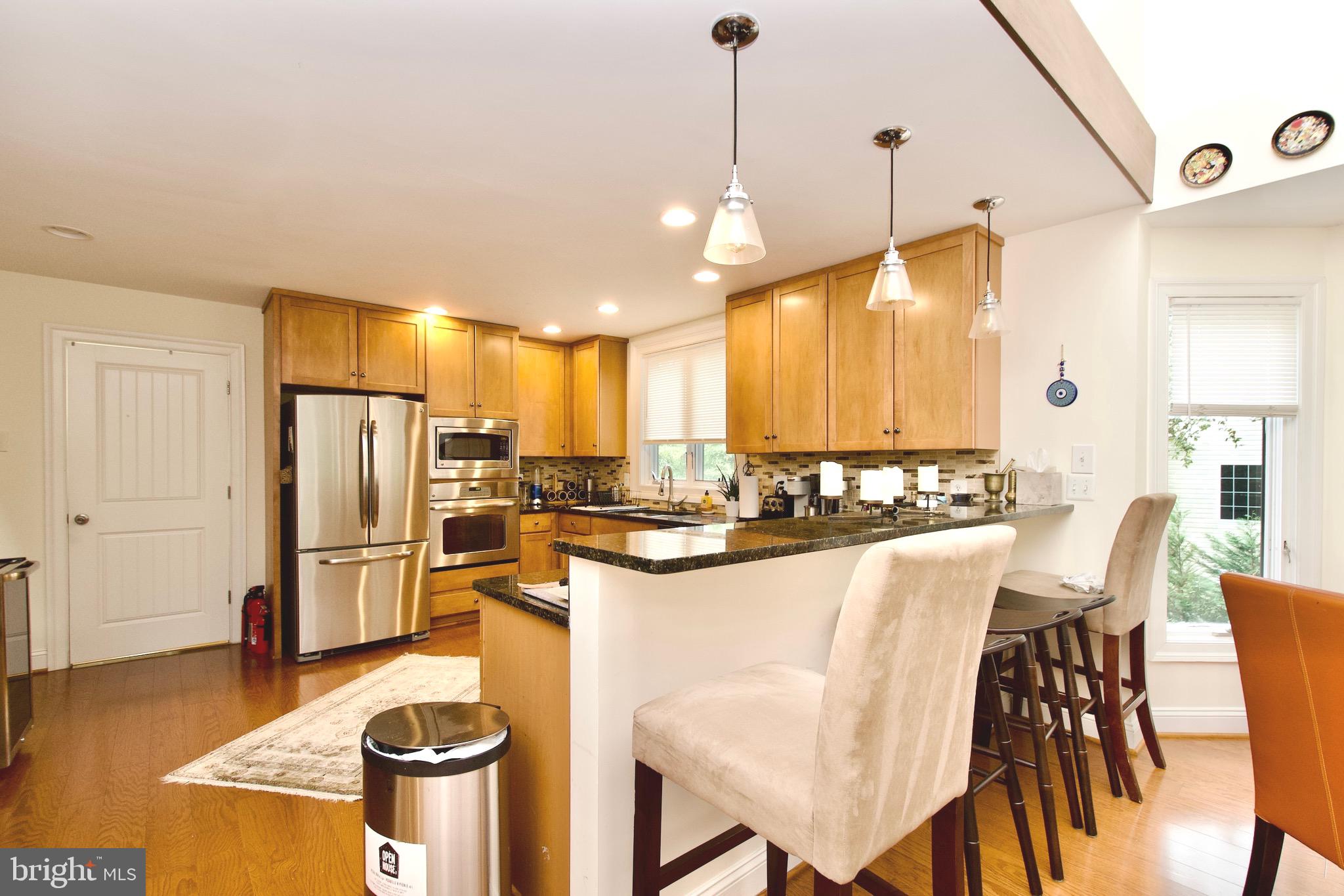 8312 Upper Spring Lane Annandale, VA 22003 - Photo 18 of 56 a kitchen with stainless steel appliances kitchen island granite countertop a refrigerator a stove a sink with a dining table and chairs
