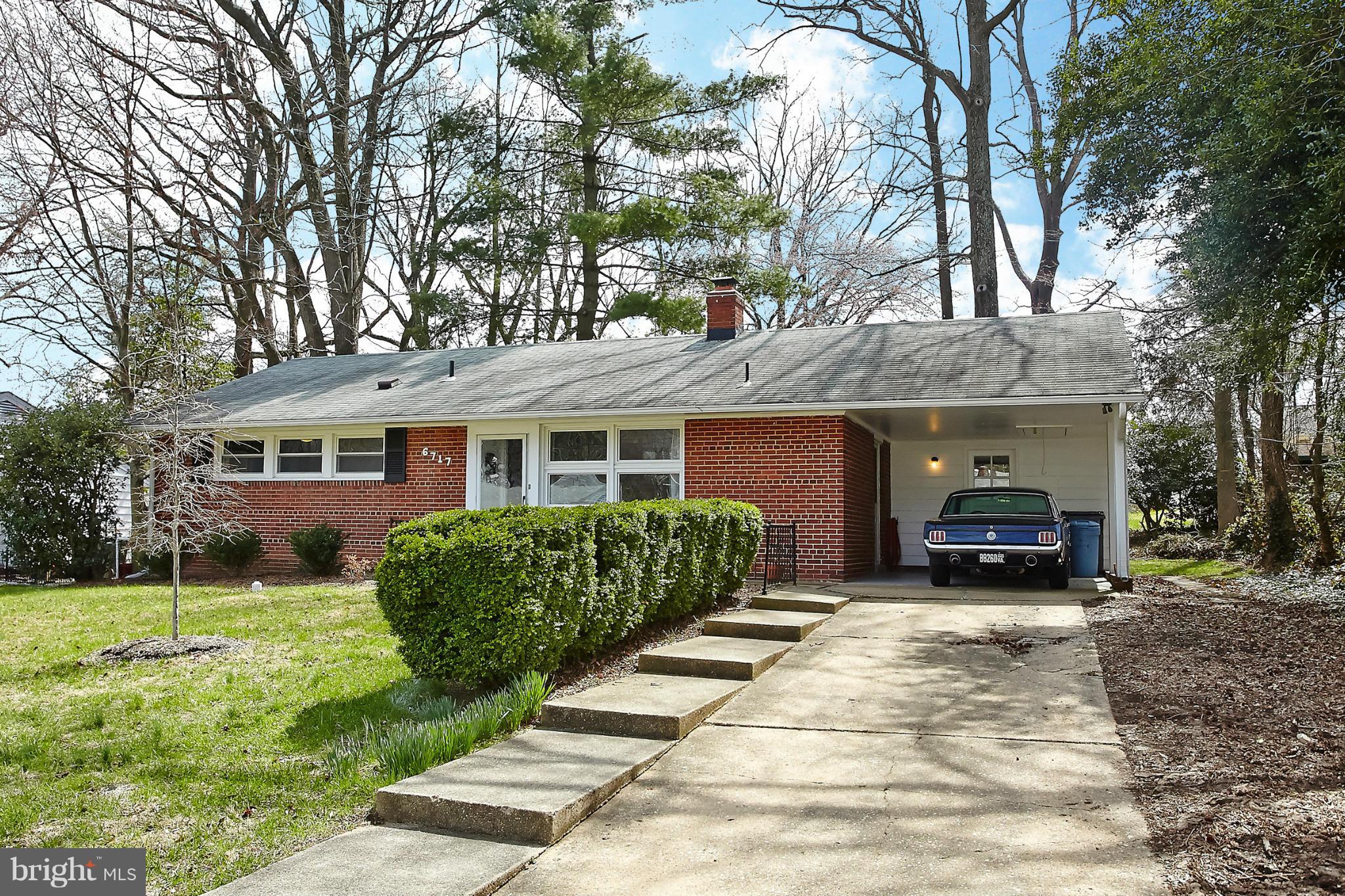 6717 Bostwick Drive Springfield, VA 22151 - Photo 1 of 12 a front view of a house with a garden and trees