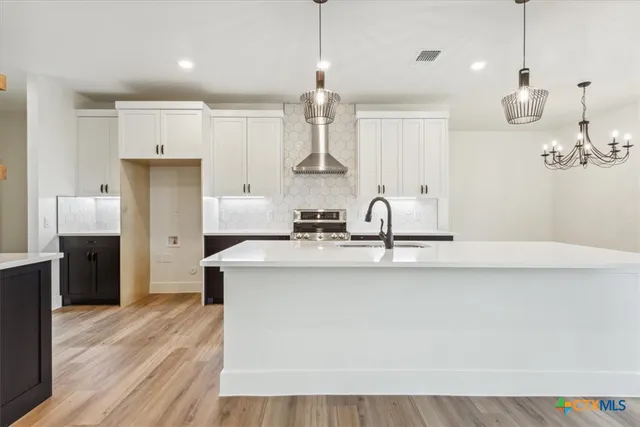 a kitchen with stainless steel appliances a sink dishwasher a refrigerator white cabinets and wooden floor