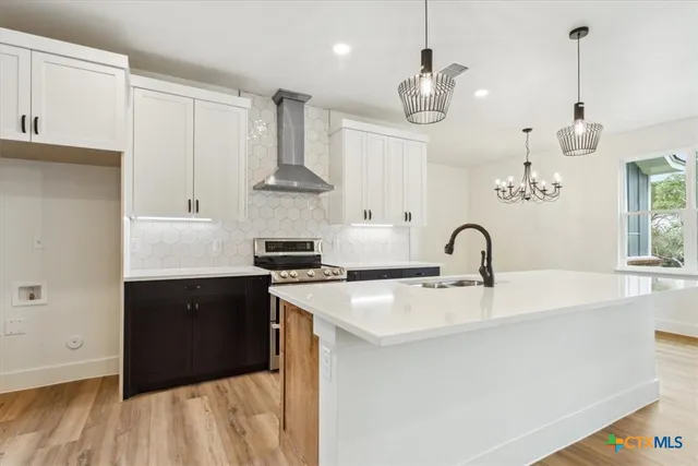 a kitchen with stainless steel appliances granite countertop a sink a stove and a wooden floors