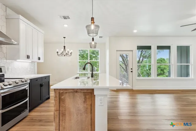 a kitchen with stainless steel appliances granite countertop a stove and a wooden floor