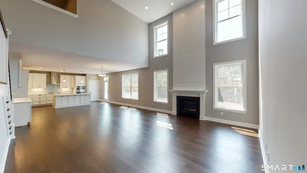 an empty room with wooden floor fireplace and windows