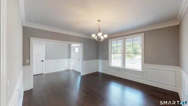 an empty room with wooden floor chandelier and windows