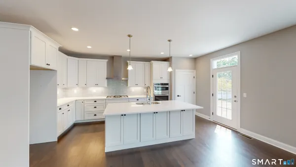 a large kitchen with white cabinets and wooden floors