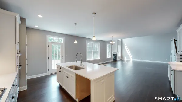 a large white kitchen with a sink a refrigerator and a large window