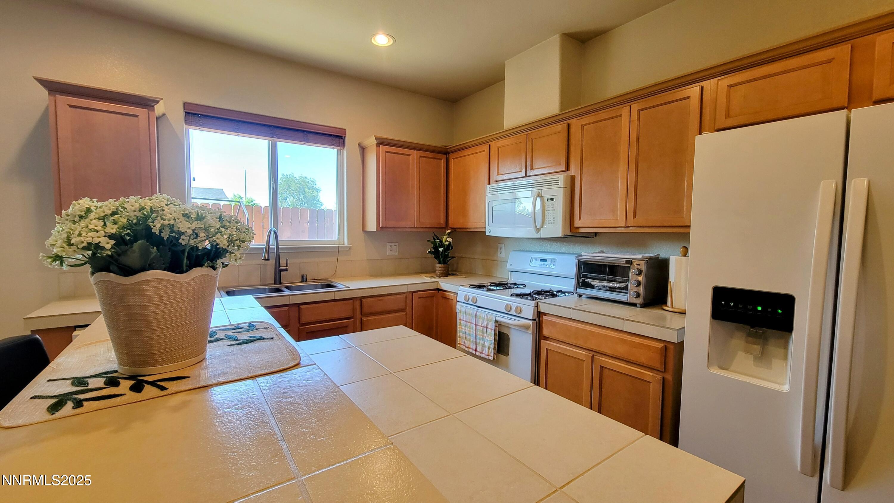 1390 Copper Leaf Drive Reno, NV 89506 - Photo 11 of 18 a kitchen with stainless steel appliances kitchen island granite countertop a refrigerator a stove a sink dishwasher and white cabinets with wooden floor