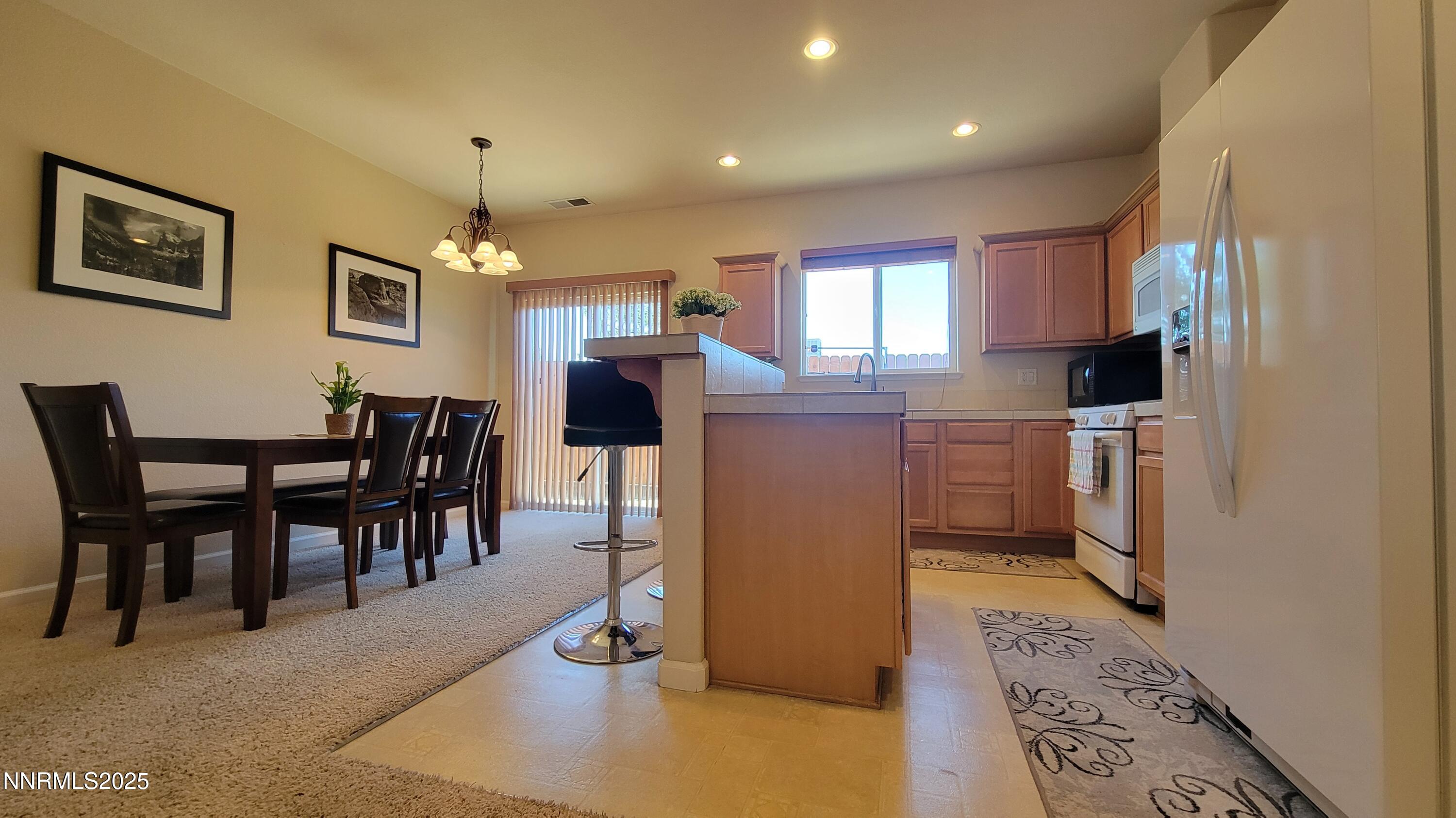 1390 Copper Leaf Drive Reno, NV 89506 - Photo 8 of 18 a kitchen with stainless steel appliances kitchen island granite countertop dining table chairs and a refrigerator