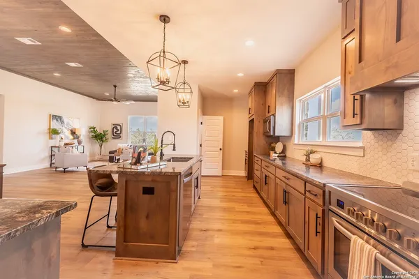 a kitchen with stainless steel appliances granite countertop a sink a stove and a wooden floors