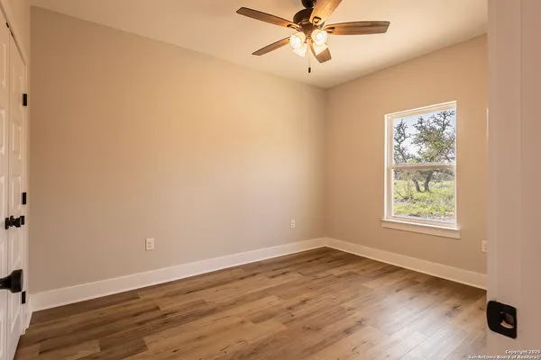 an empty room with wooden floor fan and windows