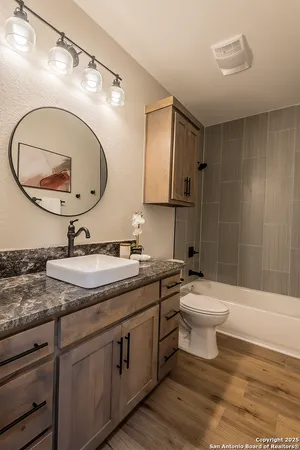 a bathroom with a granite countertop toilet a sink and a mirror