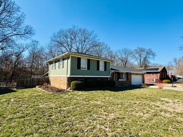 a front view of house with yard and trees in the background