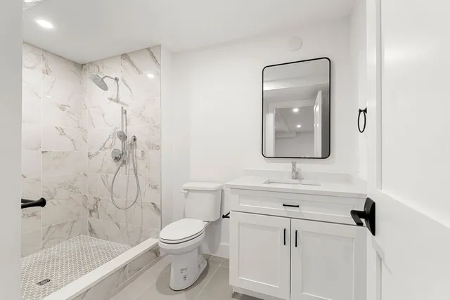a bathroom with a toilet sink vanity tub and shower