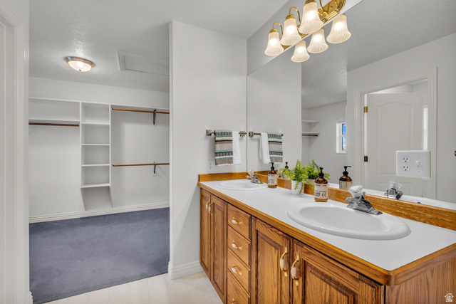 1060 West 2620th Street South Mapleton, UT 84664 - Photo 28 of 87 Bathroom featuring double vanity, a spacious closet, light carpet, and a textured ceiling