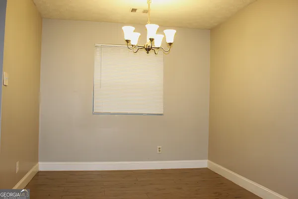 a view of a room with wooden floor and chandelier