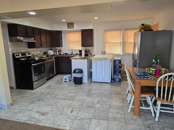 a kitchen with stainless steel appliances granite countertop a stove top oven a sink a dining table and chairs
