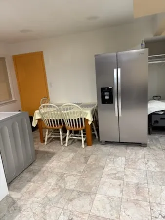 a living room with furniture a table and a refrigerator