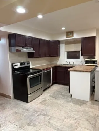 a kitchen with stainless steel appliances granite countertop a stove top oven a sink and a refrigerator