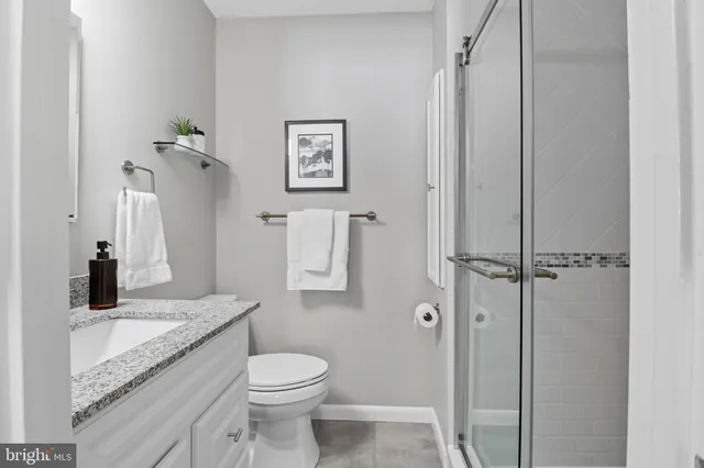 a bathroom with a granite countertop shower sink vanity and toilet