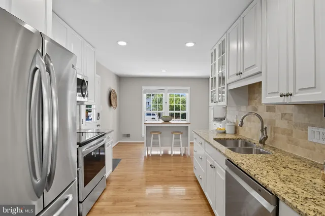 a kitchen with stainless steel appliances granite countertop a refrigerator sink and wooden cabinets