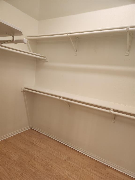 4175 Midrose Trail Dallas, TX 75287 - Photo 10 of 14 Walk-in closet featuring wood-finish flooring, white baseboards, and built-in shelving with hanging rods
