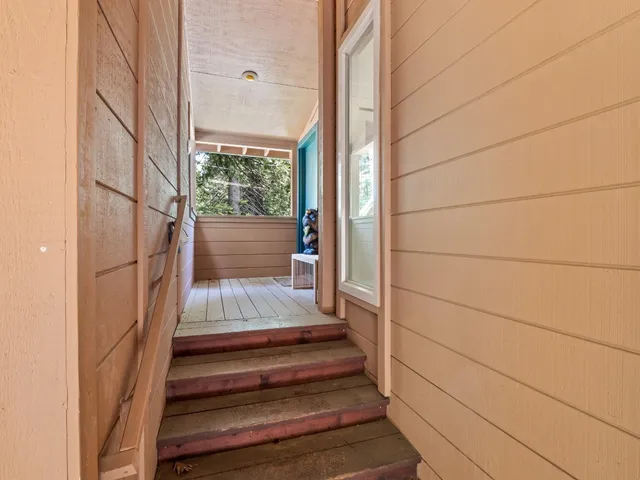 a view of hallway with window and wooden floor