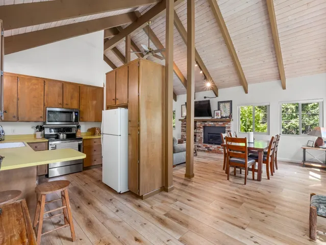 a kitchen with stainless steel appliances granite countertop a refrigerator a oven a sink and a dining table with wooden floor