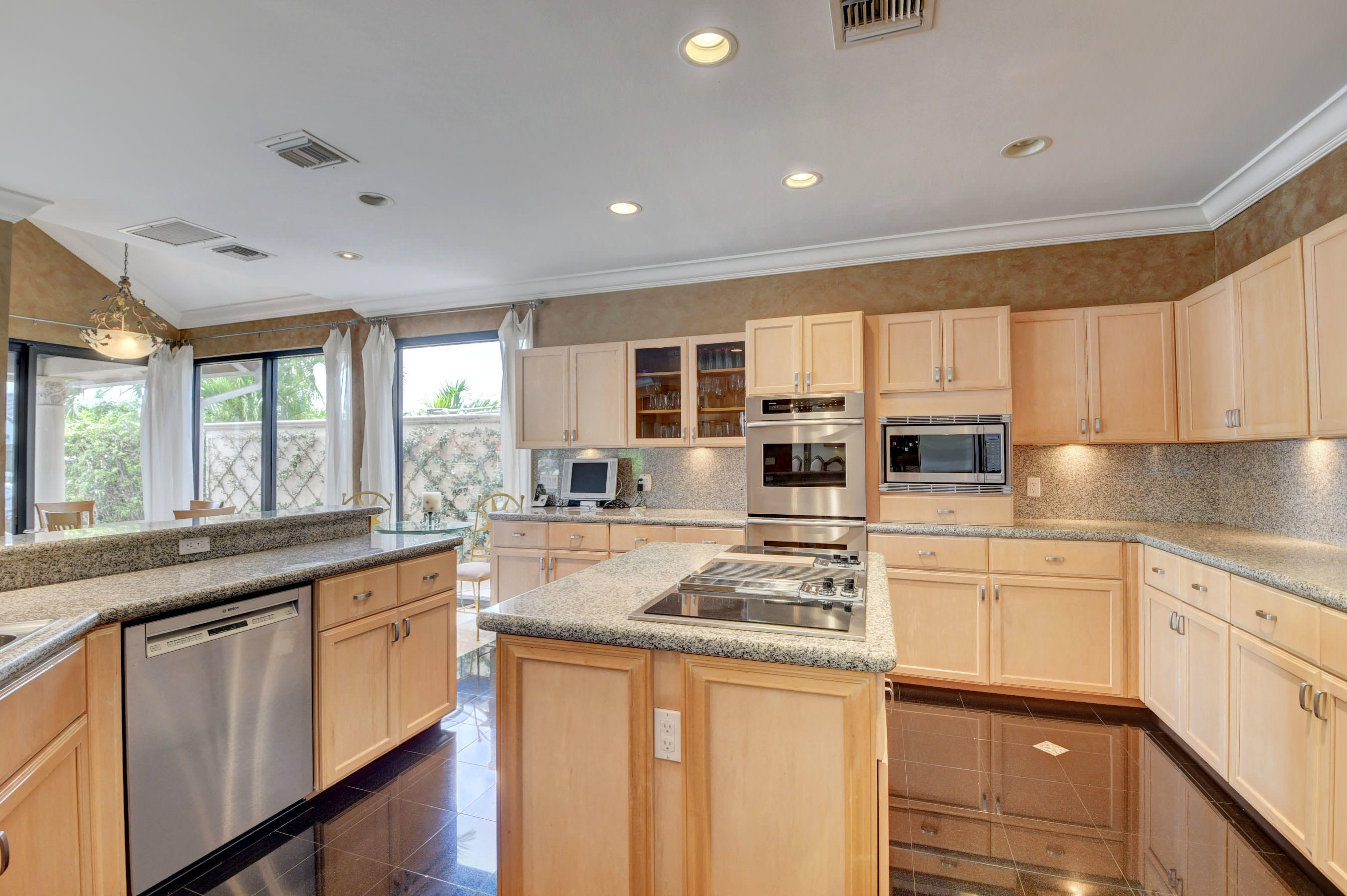 860 Northeast 79th Street Boca Raton, FL 33487 - Photo 33 of 109 a kitchen with stainless steel appliances granite countertop a stove top oven a sink dishwasher a dining table and chairs with wooden floor