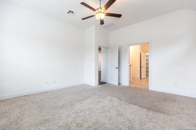 an empty room with closet and a ceiling fan