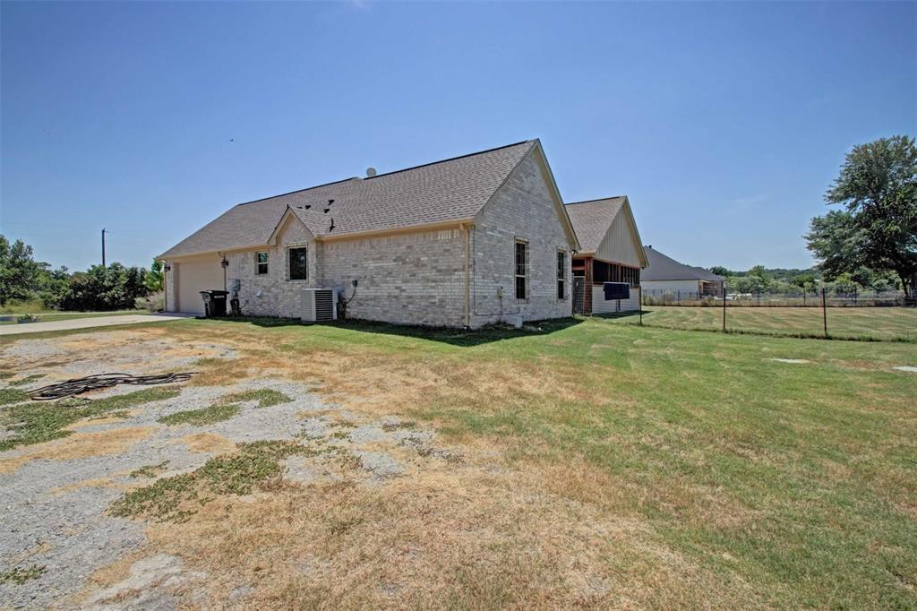 8789 Hutcheson Hill Road Springtown, TX 76082 - Photo 29 of 29 Rear view of house with an attached garage, brick siding, a shingled roof, and driveway