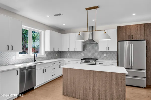 a kitchen with stainless steel appliances a sink a stove a refrigerator cabinets and a window