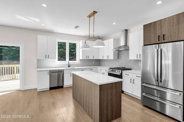 a kitchen with kitchen island granite countertop a stove a sink a refrigerator and island with wooden floor