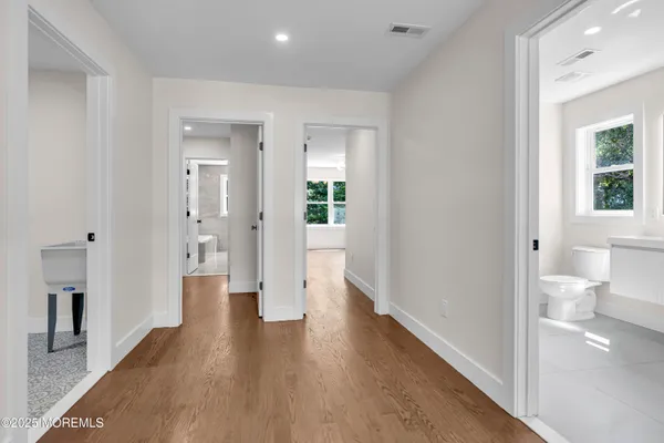 a view of a hallway with wooden floor and a bathroom