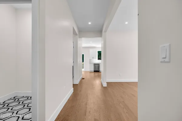 a view of a hallway with wooden floor and a bathroom