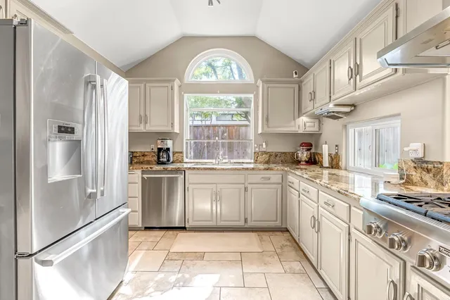 a kitchen with stainless steel appliances granite countertop a stove a refrigerator and a sink