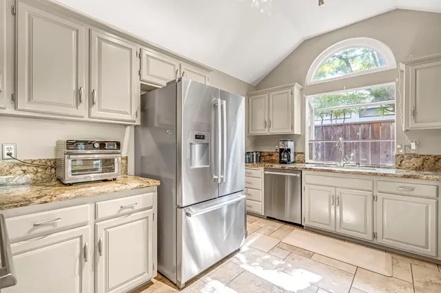 a kitchen with cabinets stainless steel appliances and a window