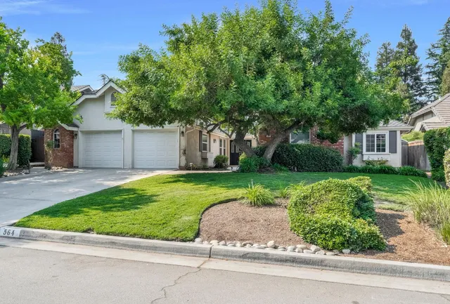 a view of a house with a yard and a large tree