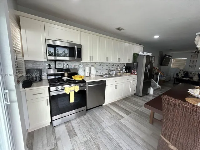 a kitchen with a refrigerator a sink a stove top oven a kitchen island and cabinets