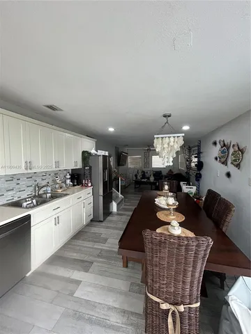 a kitchen with stainless steel appliances granite countertop a stove top oven a sink dishwasher and white cabinets with wooden floor