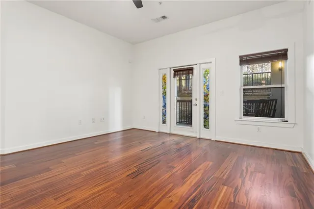 a view of an empty room with wooden floor and a window